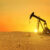 Pumpjack rig pumps oil in the desert at sunset. Dead land and sand, concept. Global warming, creative idea. Resources Energy of planet Earth.